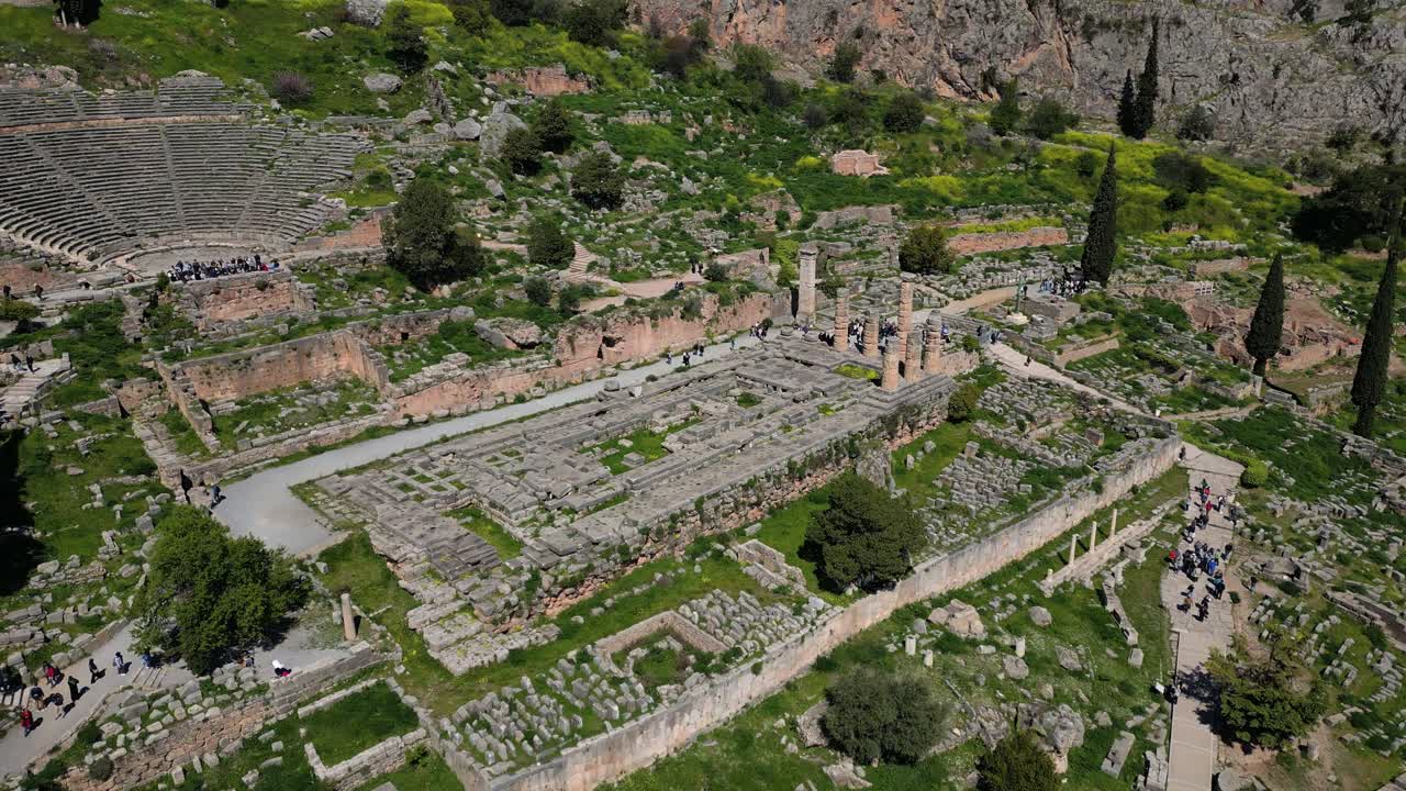 Temple of Apollo in Delphi seen from drone flying above Greek ruins and lush green hills