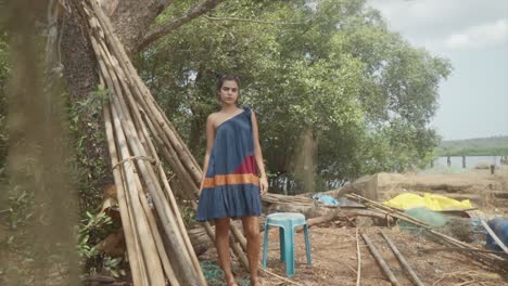 cinematic slow motion shot of a fashion model posing on a sandy beach in a blue red and orange sustainable fashion dress in goa india, slomo