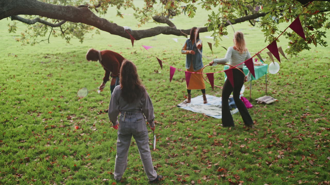 Friends playing badminton and having a picnic in the park