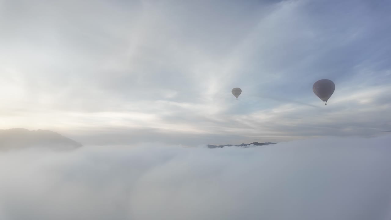 Hot air balloons floating over a foggy landscape in Vang Vieng, Laos