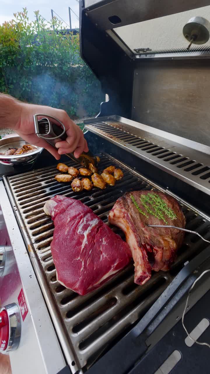 Close up of juicy steaks and chicken wings sizzling over a gas propane grill during summer grilling, vertical