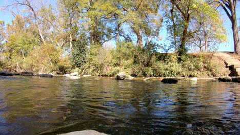 On-a-rock-in-middle-of-a-creek,-panning-left-from-stairs-leading-down-to-the-creek-to-center-of-creek