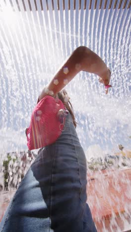 person with pink bag under cascading fountain on a sunny day