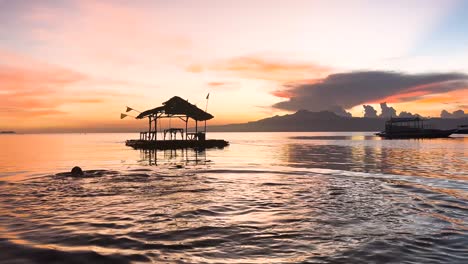 a man dives into a calm ocean and then swims away during a beautiful and colourful sunset on paliton beach in suquijor island, philippines
