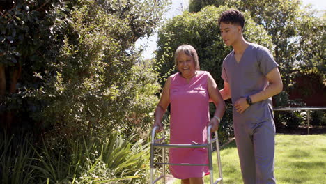 Helping senior woman with walker, male physiotherapist providing support outdoors