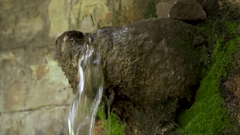 drinking fountain with clear water flowing from a paved stone on an old village, close up