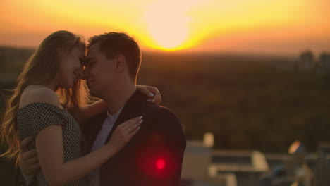 hugging standing on the roof at sunset. summer roof at sunset. a man with a girl came on a romantic date on the roof.