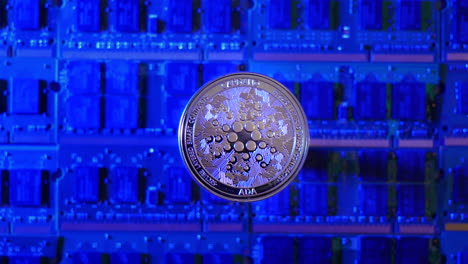 a tracking shot of cardano ada crypto currency coin hovering over a mining rig of computer chips