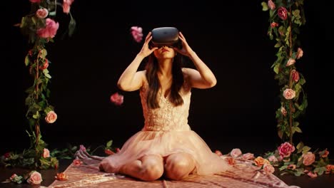 a young woman enjoys an immersive experience with virtual reality while surrounded by a floral arrangement. she sits comfortably on a mat, exploring a new digital world.
