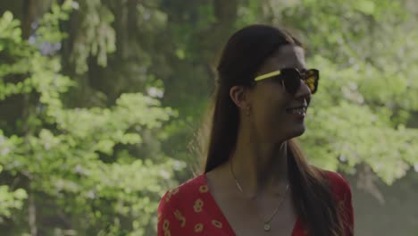 paseo por el bosque encantado: medio plano de una mujer con un vestido rojo vibrante que lleva una rama de enebro y camina a través de un bosque exuberante como de cuento de hadas en medio de la mística niebla y niebla matutina
