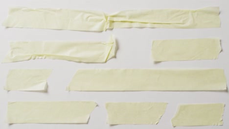 video of close up of multiple torn piece of yellow paper with copy space on white background