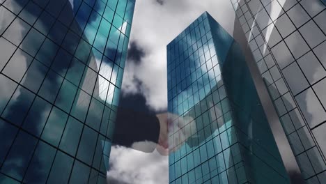 Mid-section-of-businessman-and-businesswoman-shaking-hands-against-tall-buildings-in-background