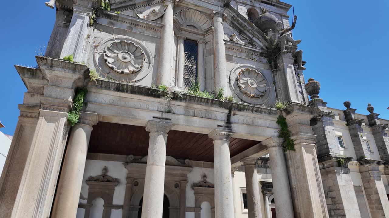 Panning across detailed Church of Nossa Senhora da Graça facade with columns and statues in Evora, tilt up