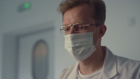 focused doctor writing notes at modern hospital workplace with computer.