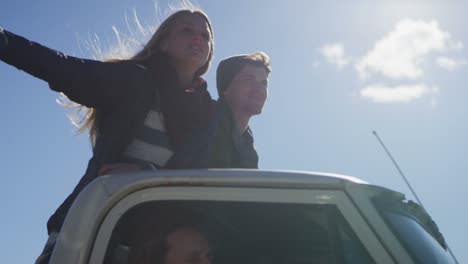 una pareja se para en la cama de una camioneta mientras conduce a lo largo de un camino rural 2