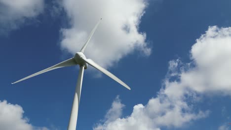 Tracking-Shot-With-Pan-Up-Of-Wind-Turbines-Spinning-On-A-Sunny-Day