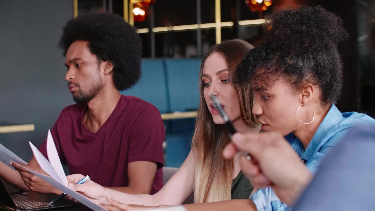 Kolegové z kanceláře analyzují dokumenty během obchodní schůzky.