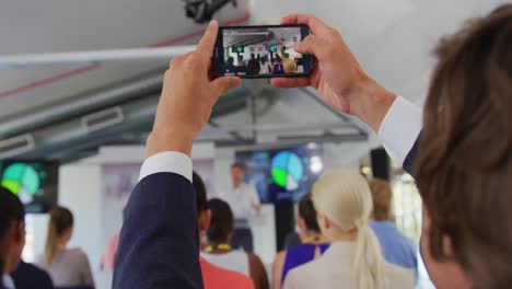 Man-in-audience-at-a-business-conference-filming-with-smartphone