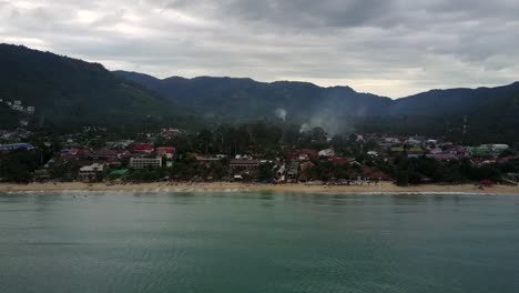 Drone-shot-of-a-beach-on-Koh-Samui-Island-as-smoke-rises-from-the-village