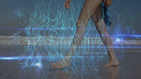 animation of light trails over caucasian woman walking at beach
