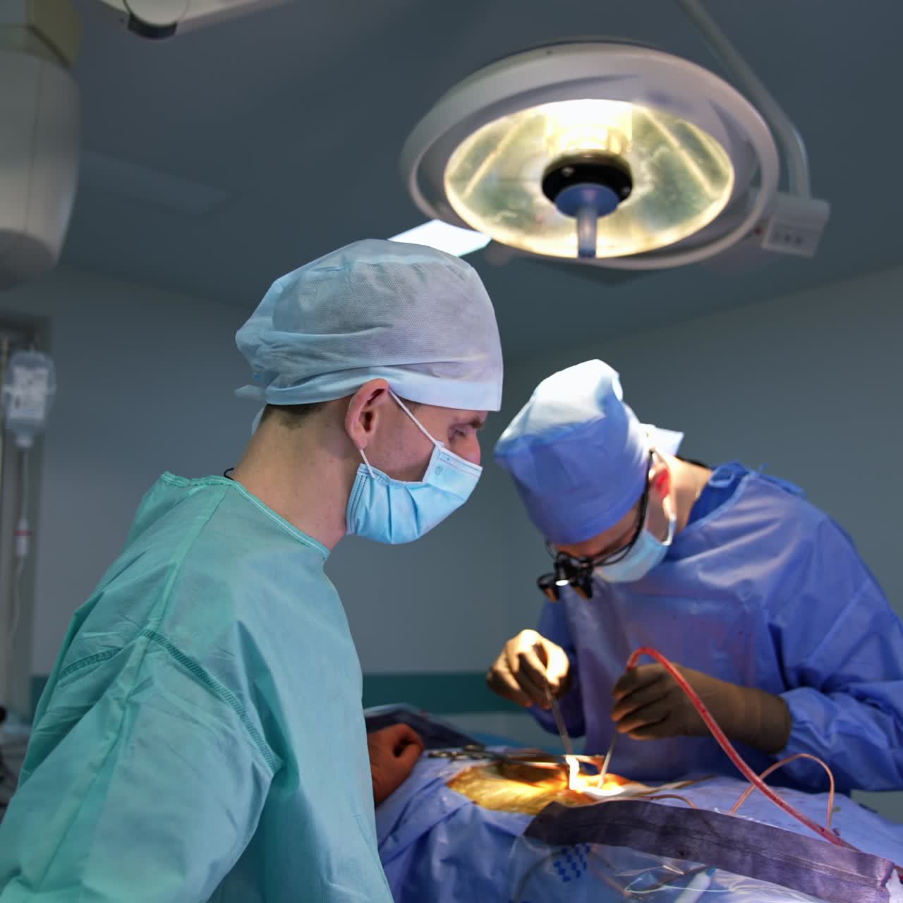 Surgeon does the precise work at operation using tools in both hands. Helping assistants standing beside the patient