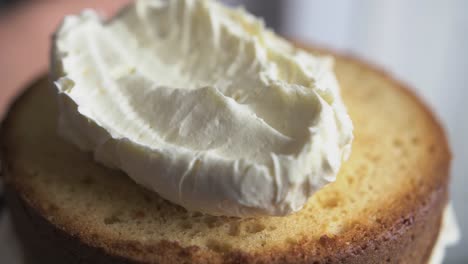 baker adds buttercream to sponge layer slow mo