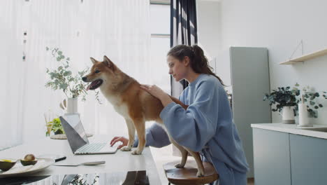 young female working with her laptop while holding on to her cute dog 1