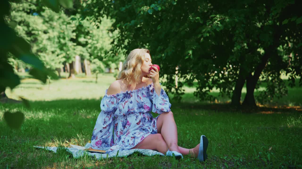 Ung kvinde slapper af i parken og spiser et frisk æble