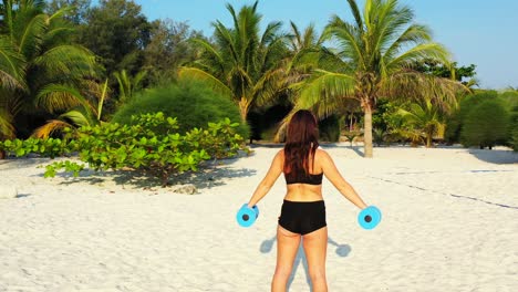 young woman practicing gymnastics weight lifting on calm exotic beach with white sand on beautiful sunlight of morning in myanmar