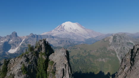 Aerial-footage-flying-backwards-through-the-rocky-ridges-of-the-Cascade-Mountains-with-Mount-Rainier-in-the-background