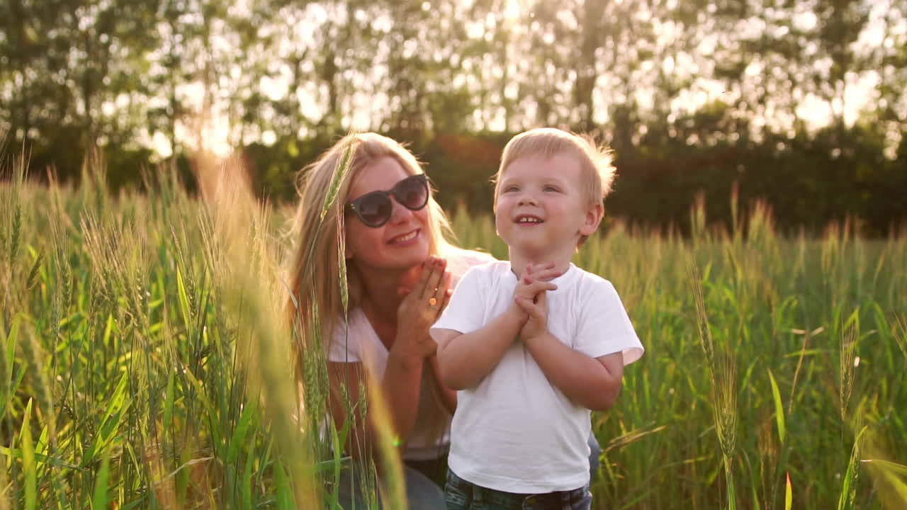 The concept of a happy family. In the rye field, the kid and his mother are fond of smiling at each other in spikelets in the backlight