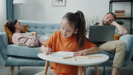 girl drawing at home with parents relaxing
