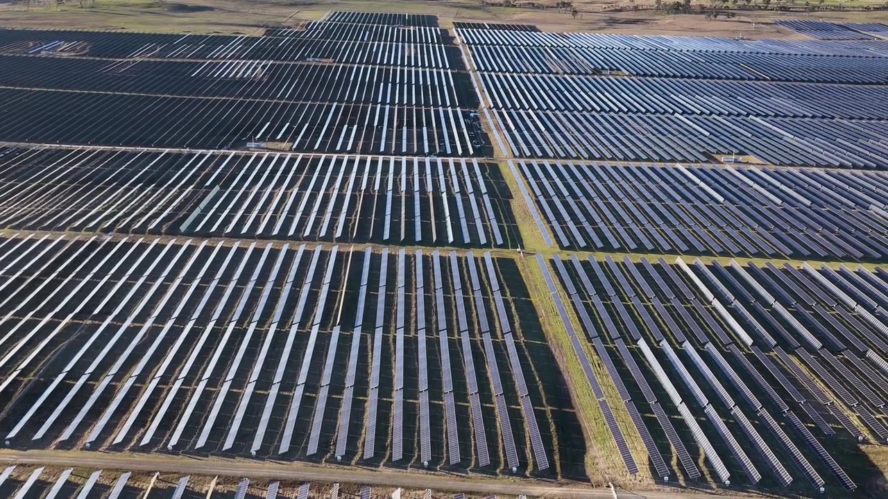 Luftfoto i fugleperspektiv over rækker af solcellepaneler, der genererer ren vedvarende energi i Australien