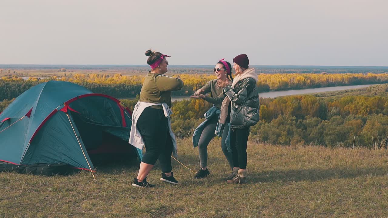 ⁇ 한 여자가 강의 천천히 움직이는 텐트에서 친구들과 춤을 춘다.