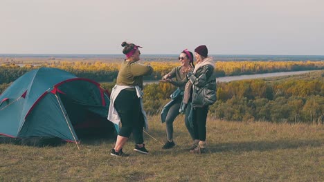 plump woman dances with friends by tent at river slow motion