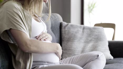 mujer embarazada masajeando el vientre y escuchando música