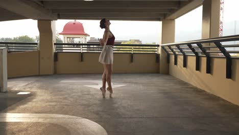 girl wearing pointe shoes dancing alone in a parkade