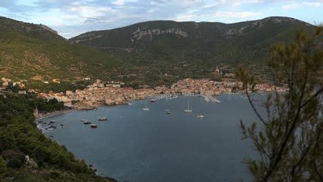 Komiza,-Vis-Island,-Croatia,-old-town-by-mountains-and-sea,-rising-shot