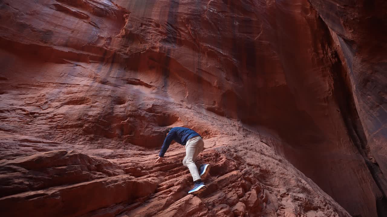 Man Climbing Up on Limestone Cliff in Narrow Slot Canyon, Utah USA