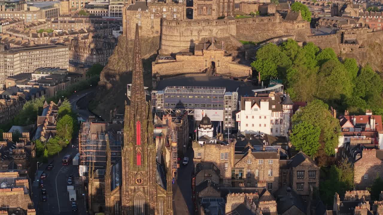 A cinematic drone shot starting from The Hub and gradually revealing the majestic Edinburgh Castle and the surrounding cityscape
