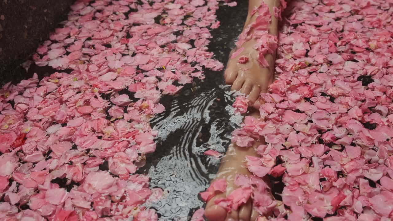 spa, las piernas de una mujer irreconocible disfrutando de un baño con pétalos de flores