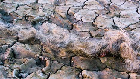 Drought-abandoned-fishing-net-climate-change-impact-cracked-earth-soil