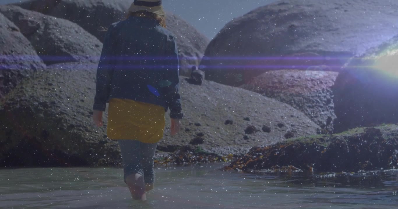 Person Walking Barefoot Through Shallow Water Near Large Coastal Rocks