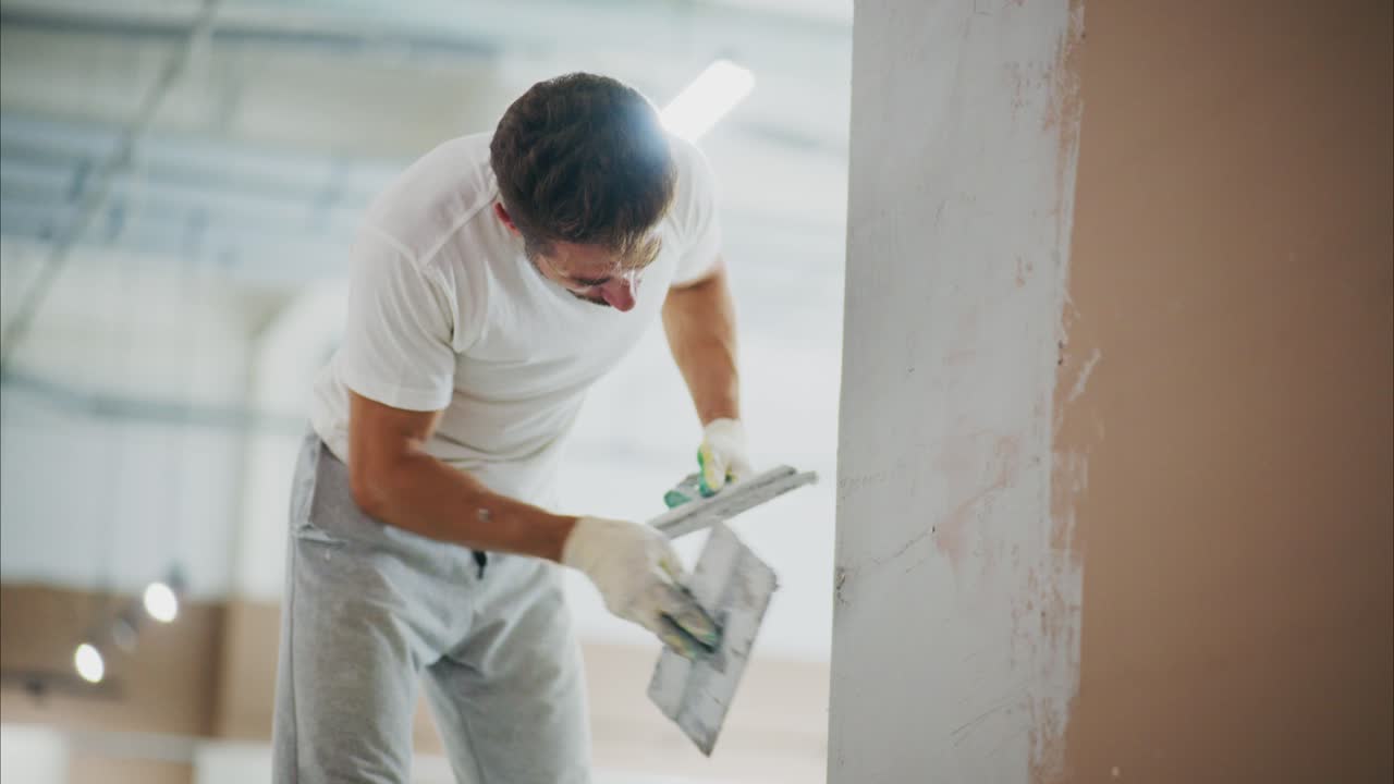 A Skilled Worker Perfects a Wall Finish with Precision in a Brightly Lit Space, Showcasing Expert Techniques in Home Improvement and Interior Design