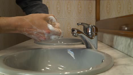 Close-up-of-male-hands-being-carefully-washed-over-bathroom-sink