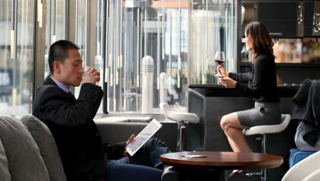 Side-view-of-asian-businessman-drinking-whisky-and-working-on-digital-tablet-in-a-modern-hotel-4k