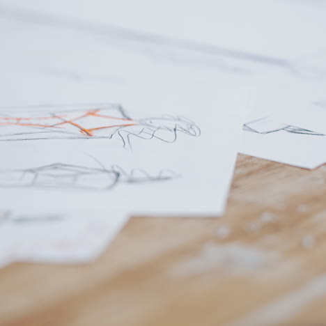 workplace of a seamstress on the table with some sketches and meter. creative drawings of a tailor on white papers and a blue tape measure on the wooden background. close-up.