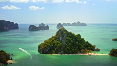 vista superior de la pequeña isla cubierta de maleza en tailandia, bote de cola larga que se aleja