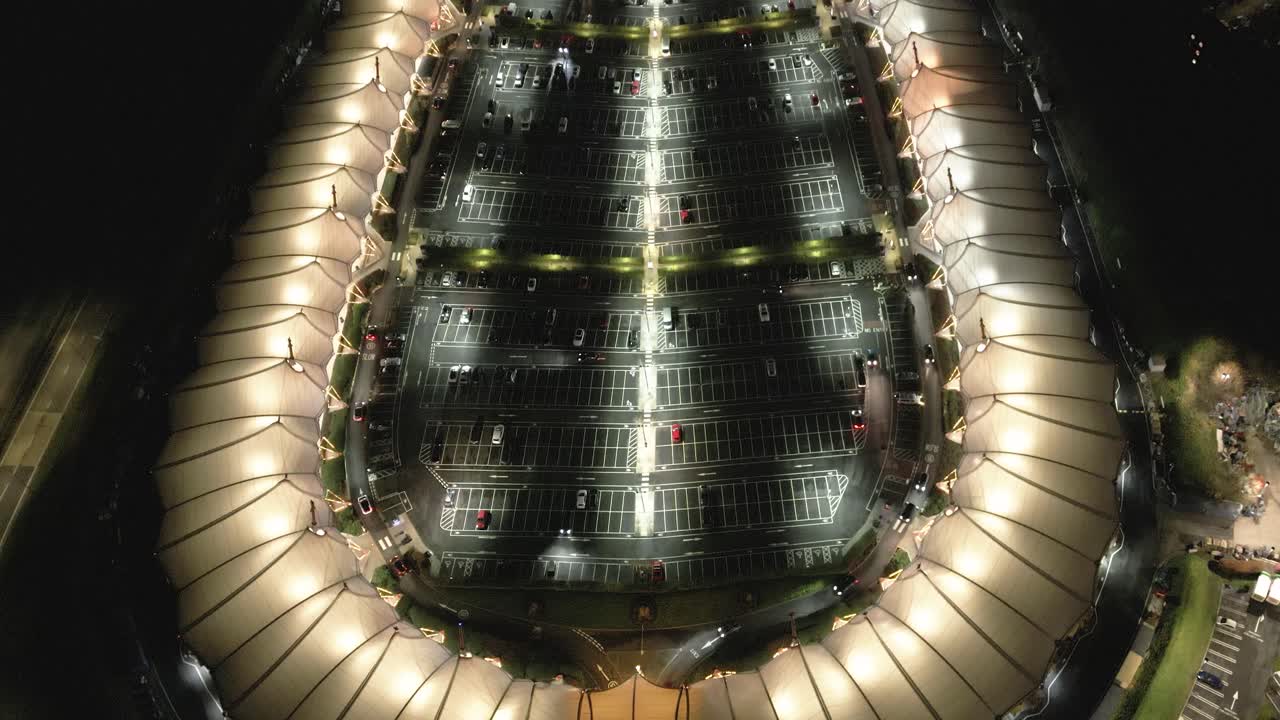 vista aérea inclinada hacia arriba sobre mcarthur glen iluminada por la noche, diseñador de lujo, tienda de compras y estacionamiento, ashford, kent