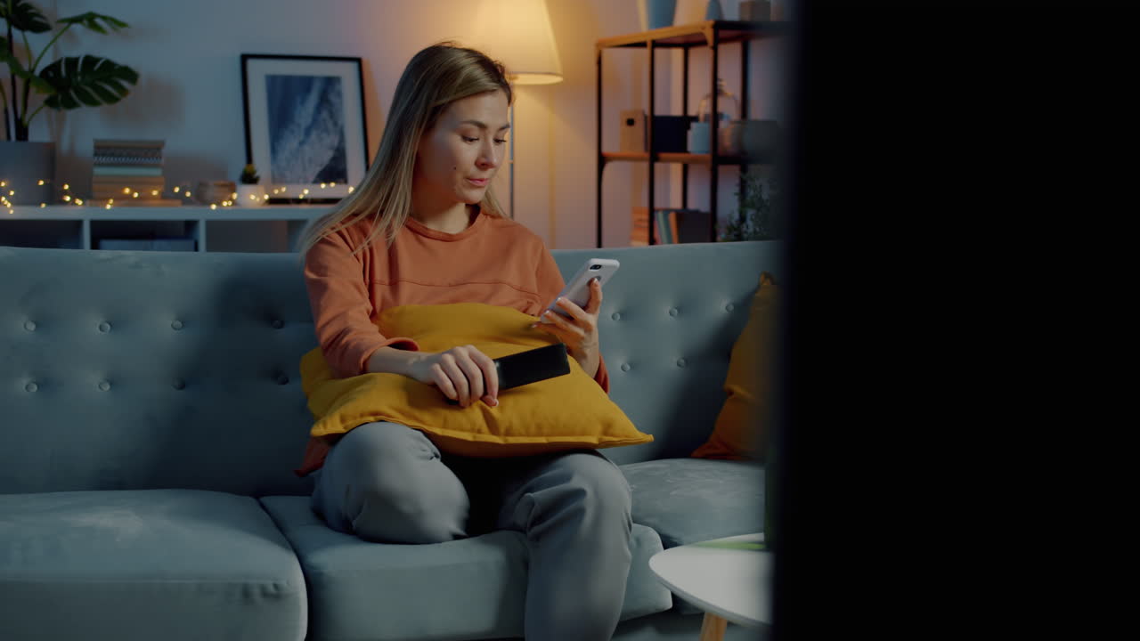 Woman Relaxing on Couch, Watching TV and Using Phone